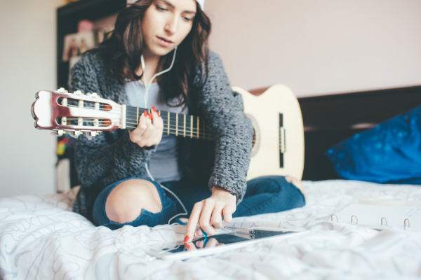 Junges Mädchen lernt online Gitarre spielen