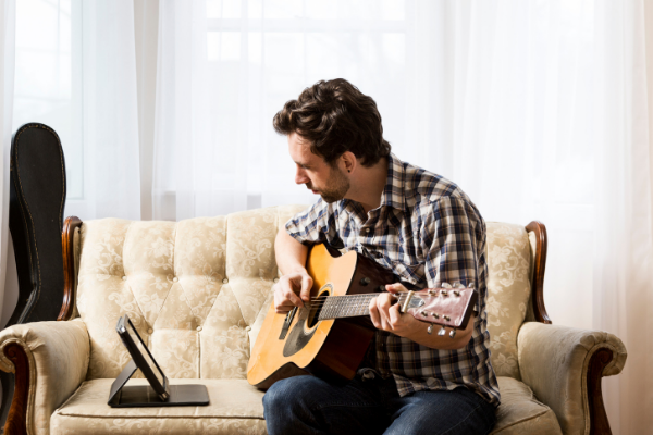 Mann lernt digital Gitarre spielen