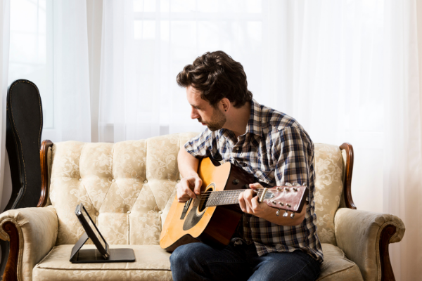 Mann lernt digital Gitarre zu spielen